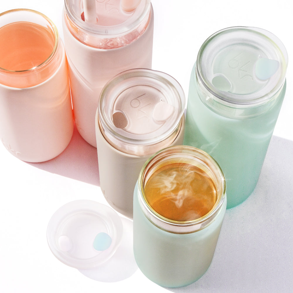 Reusable insulated glass and silicone tumblers in opaque ballet pale peachy pink, opaque light fawn beige, and sheer mint sea glass.