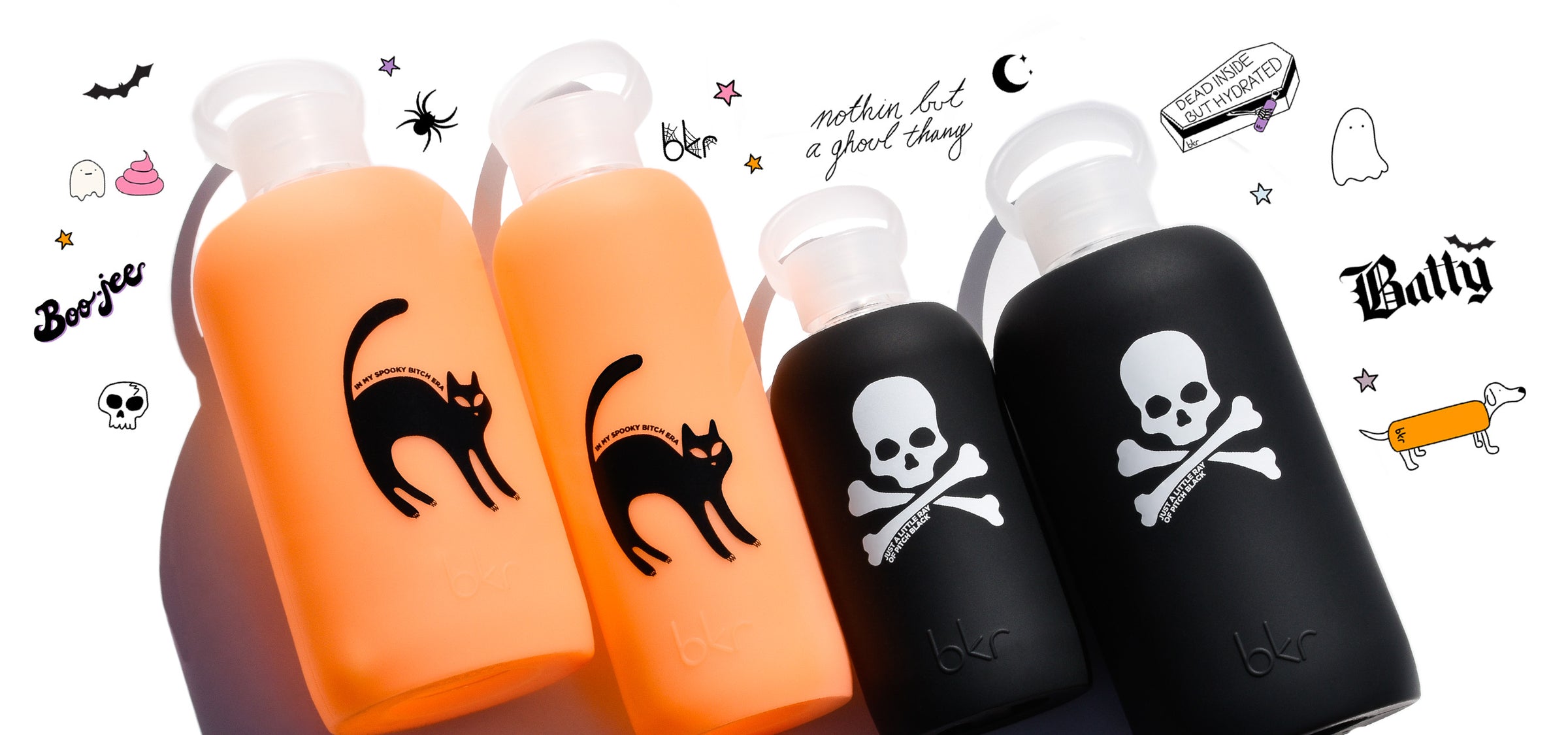 Reusable glass and silicone water bottles in sheer orange cream soda with black cat print and opaque black with white skull print.