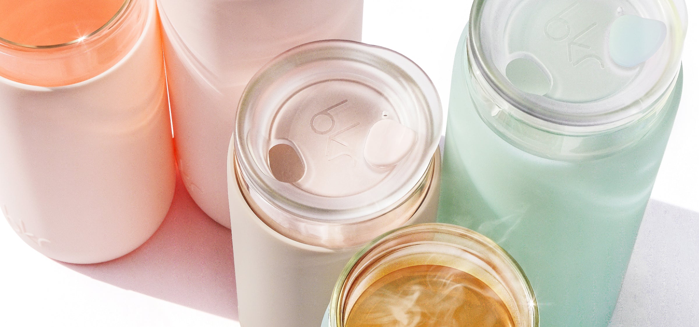 bkr glass double-walled insulated glass tumblers with silicone sleeves in opaque ballet pale peachy pink, opaque light fawn beige, and sheer mint sea glass.