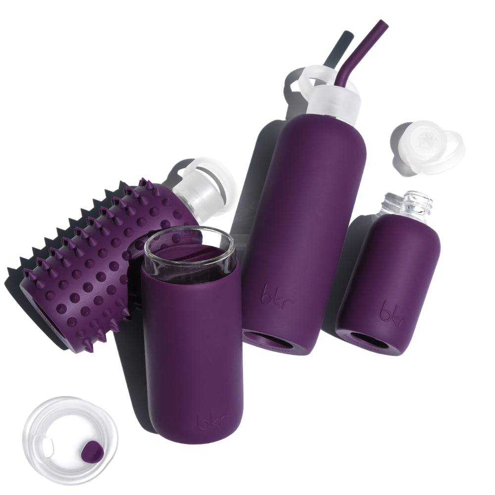 Reusable glass and silicone water bottles in opaque blackcurrant purple.