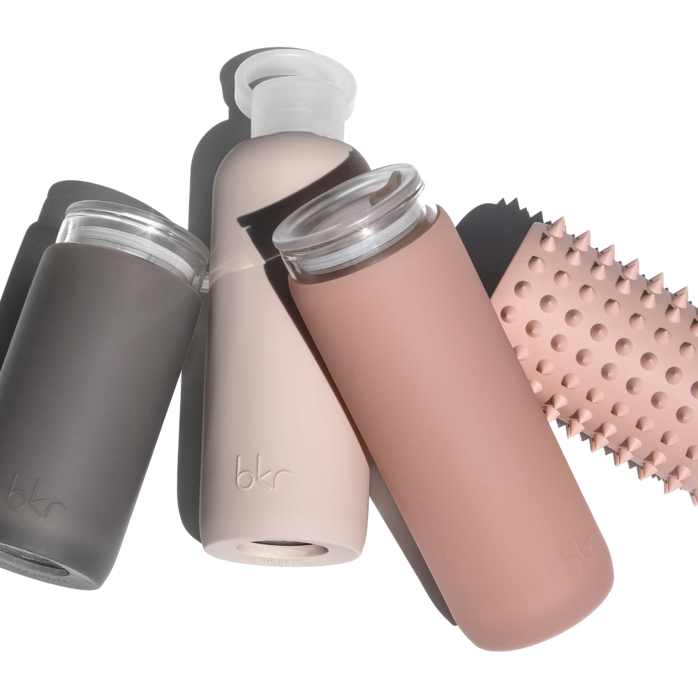 Reusable glass and silicone water bottles and insulated tumblers in natural neutrals.