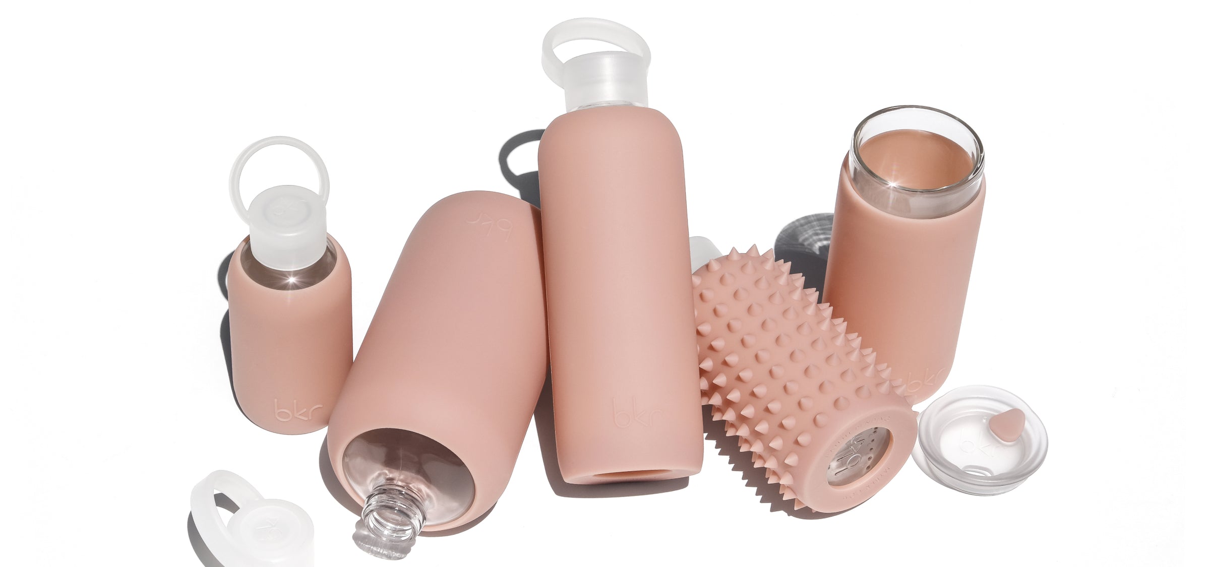 Reusable glass and silicone water bottles and insulated tumblers in demi sheer café au lait beige.