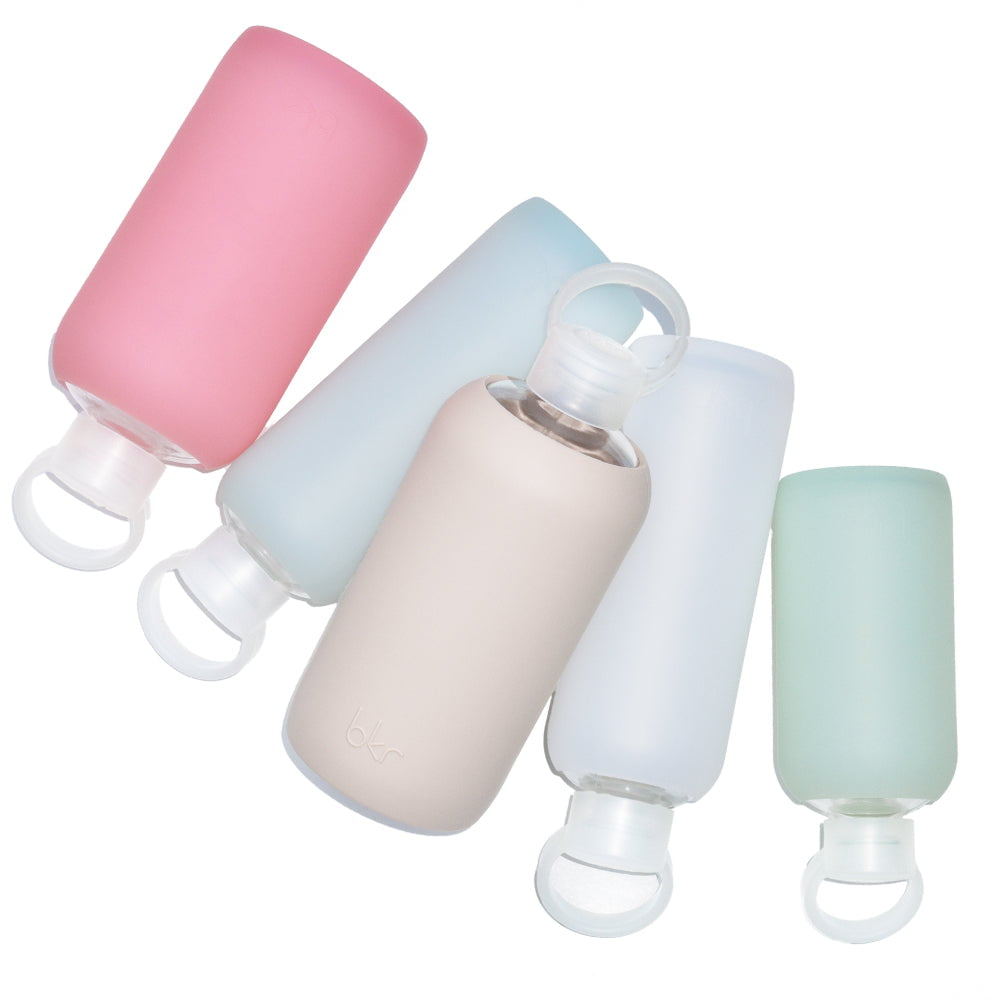bkr glass and silicone reusable water bottles in sheer sugary warm pink, sheer glacial milk blue, opaque light fawn beige, sheer white, and sheer mint sea glass.