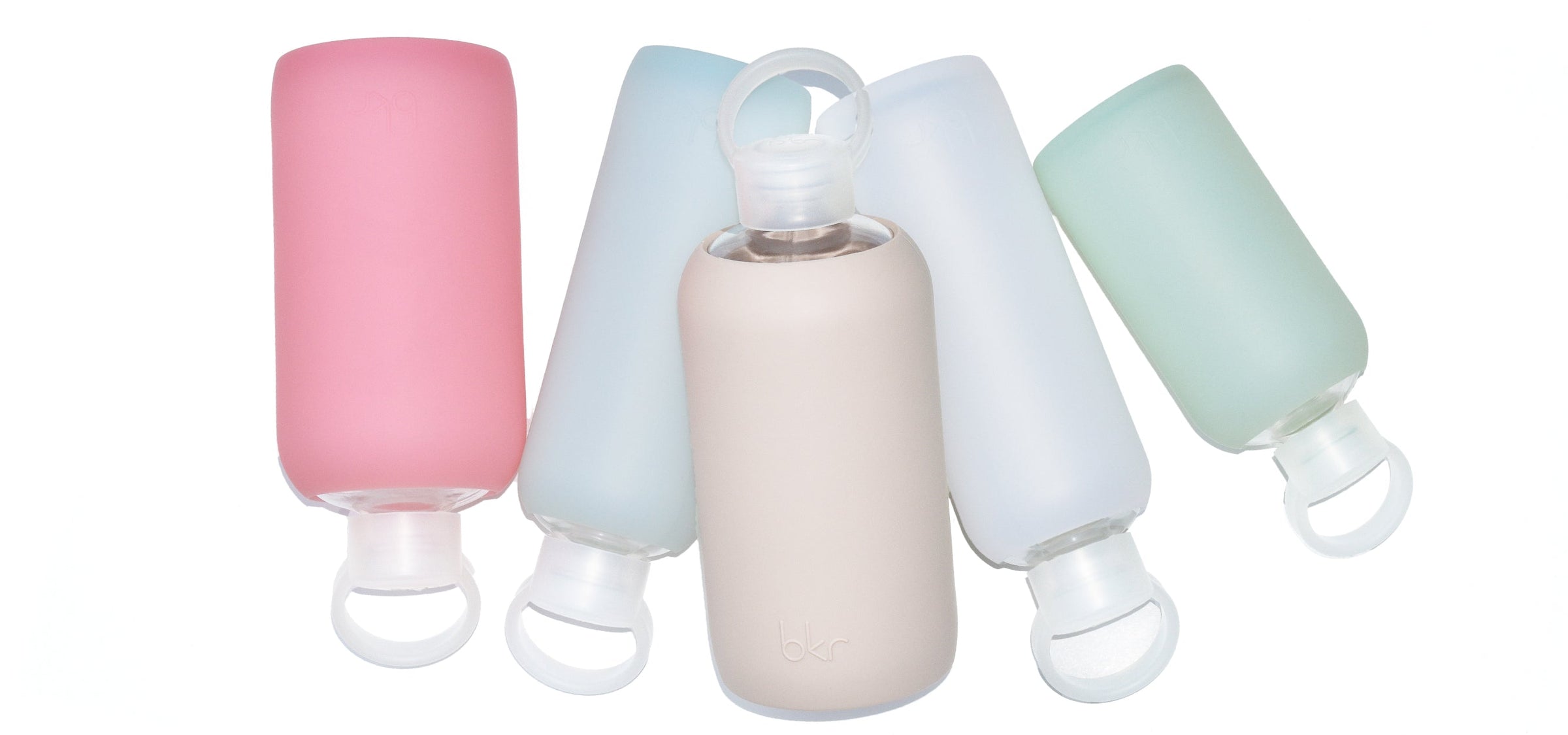 bkr glass and silicone reusable water bottles in sheer sugary warm pink, sheer glacial milk blue, opaque light fawn beige, sheer white, and sheer mint sea glass.