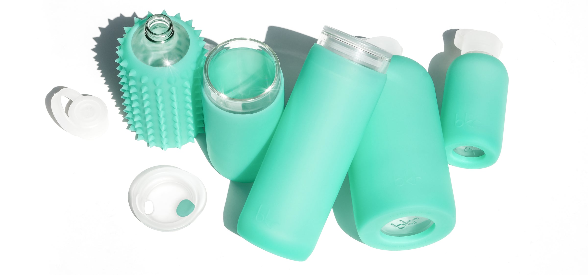 Reusable glass and silicone water bottles and insulated tumblers in sheer tropical shallow sea green.