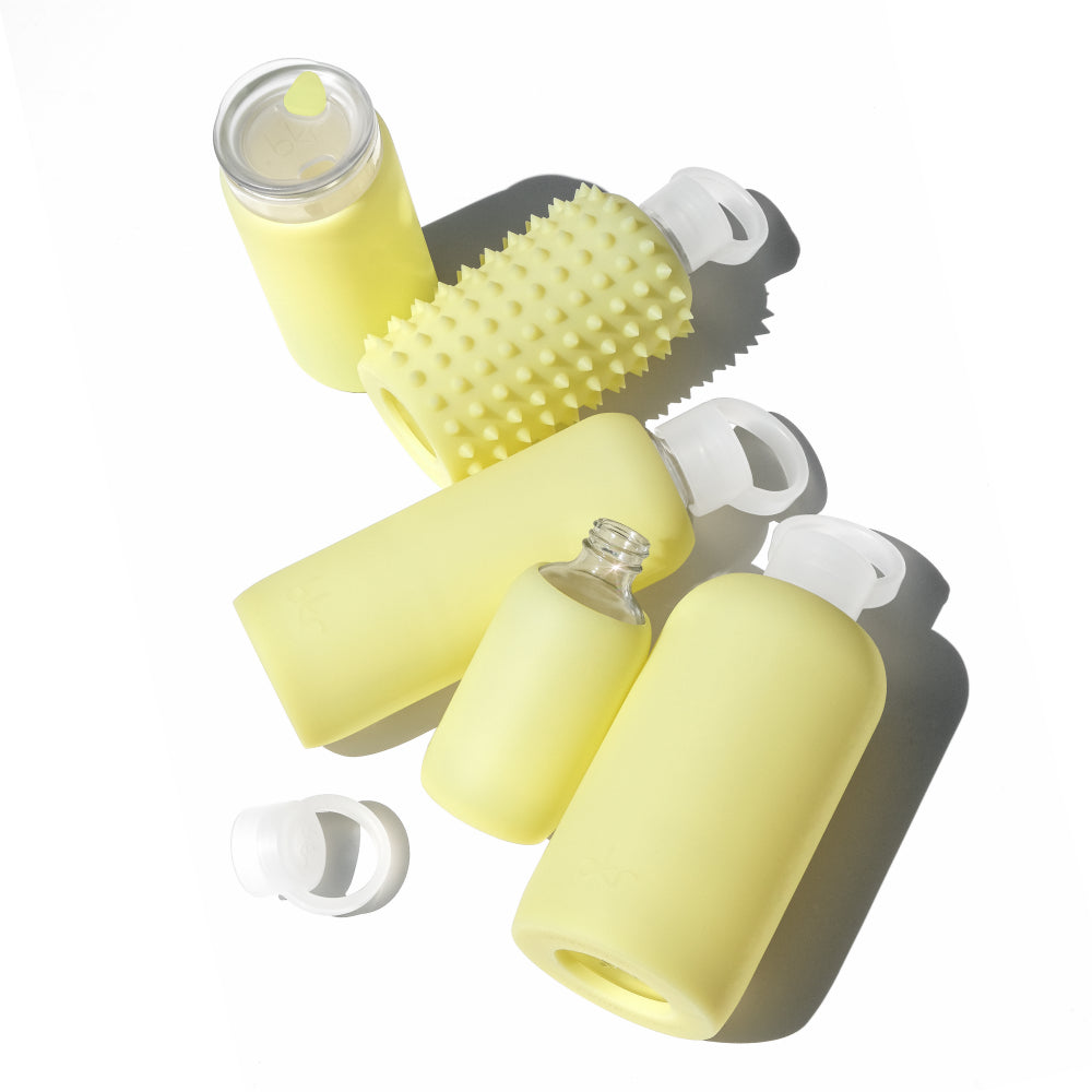 Reusable glass and silicone water bottles and insulated tumblers in sheer lemonade yellow.