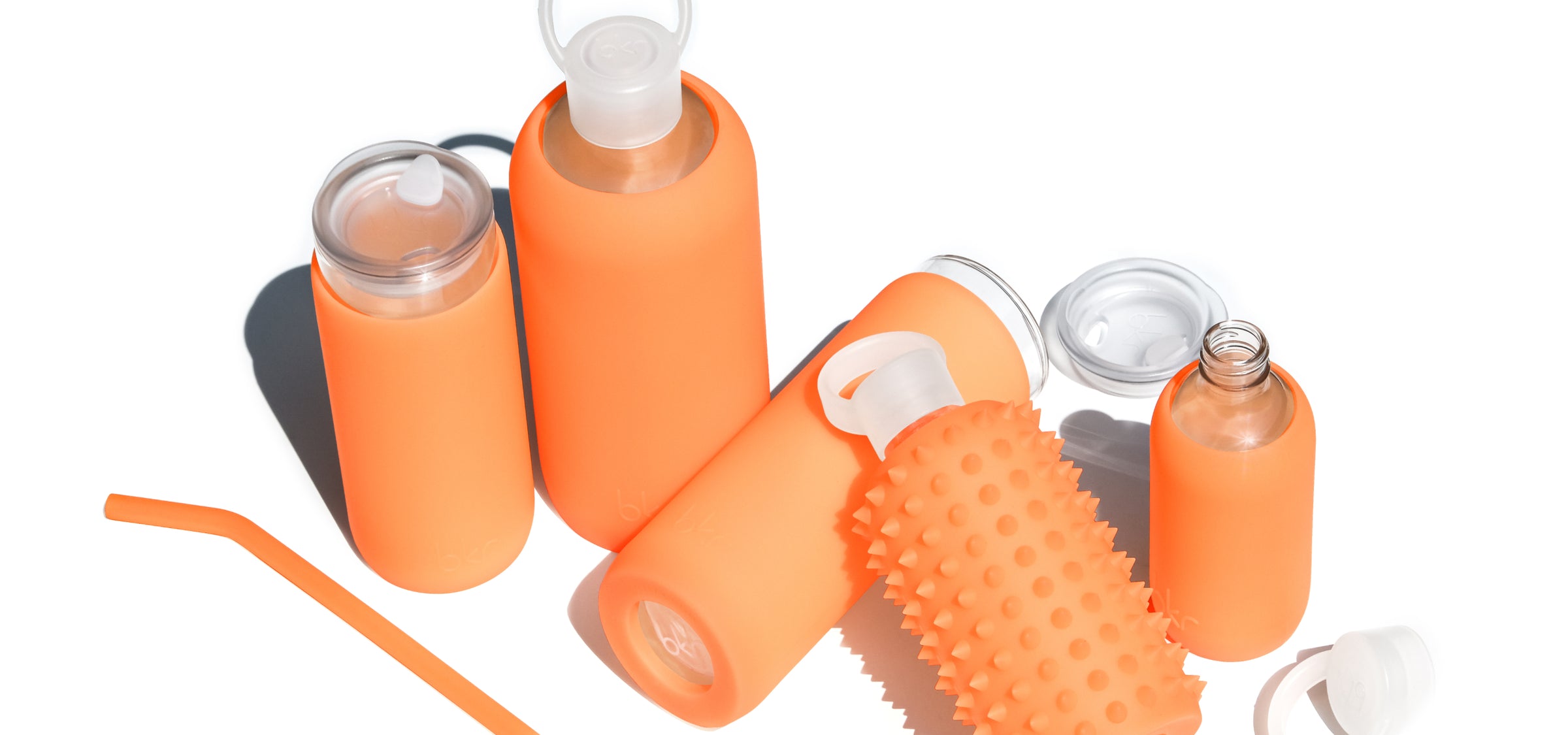 Reusable glass and silicone water bottles in sheer orange cream soda.