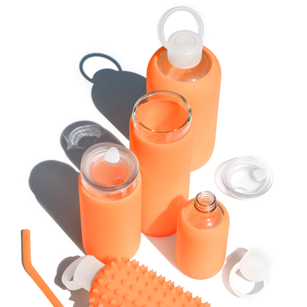 Reusable glass and silicone water bottles in sheer orange cream soda.