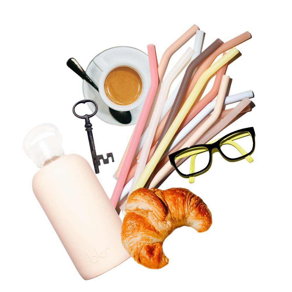 bkr glass and silicone water bottle with assorted straws with an assortment of desk items